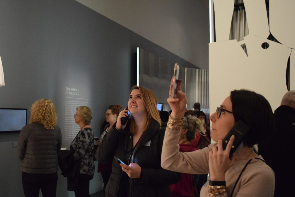 A CSU guest listens to the audio tour while viewing Dior: From Paris to the World.