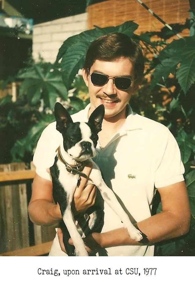 A young man in sunglasses holding a small dog and smiling. Photo taken in 1977.