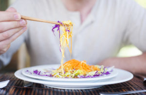 Close up of a man enjoying a meal with chopsticks in a restaurant