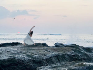 Megan Majors in a yoga pose on ocean rocks