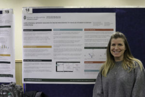 Kelly McKenna poses in front of the C-ALT team's research poster