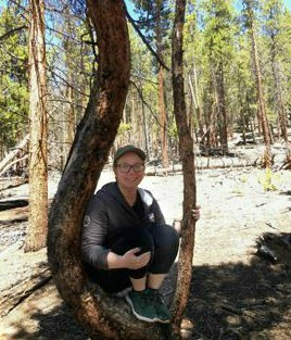 Shea McCowen sitting in the base of a tree