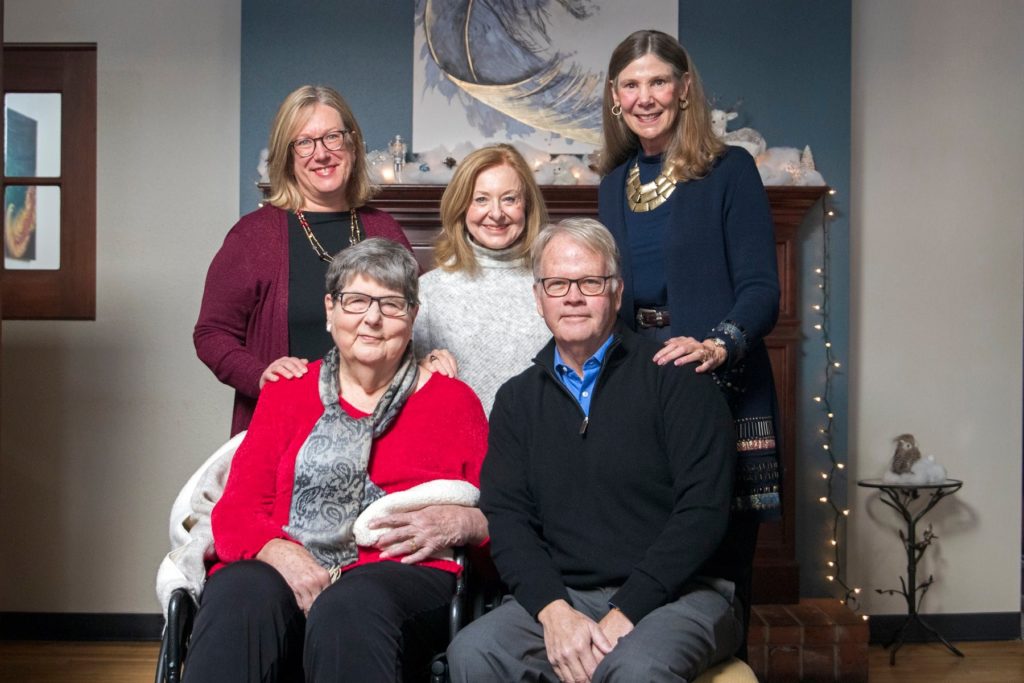 Current and former deans of the College of Health and Human Sciences pose for a photo in front of a fireplace mantle. Four are women, one is a man. 