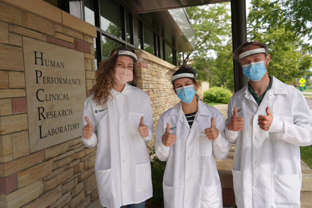 Group of 3 researchers standing outside the HPCRL lab in lab coats and masks
