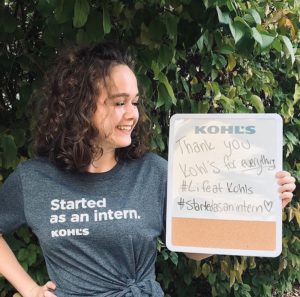 Bee Pettner smiles in a "started as an intern" shirt courtesy of her new employer, Kohl's. She holds a decorative white board.