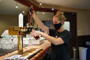 Student pouring beer into glass from tap
