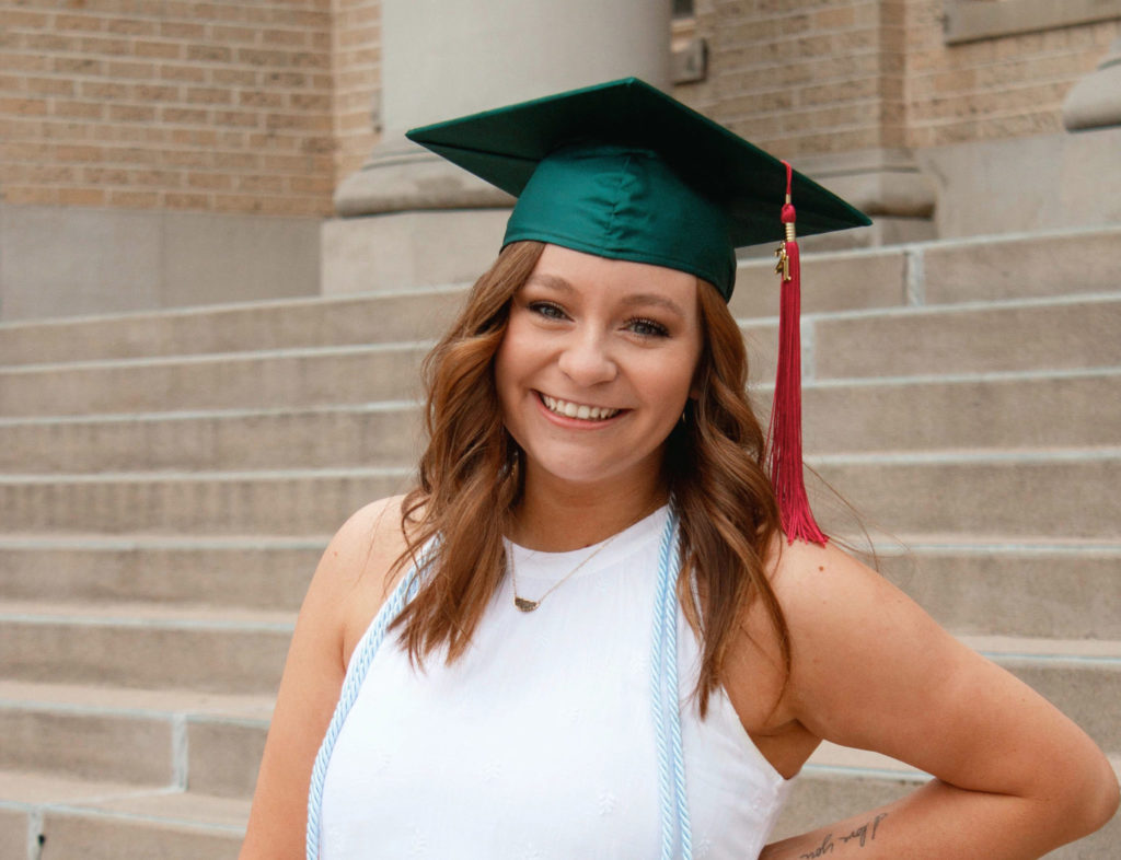 CaraShea Hughes poses in her graduation cap on the steps of the Administration Building at Colorado State University