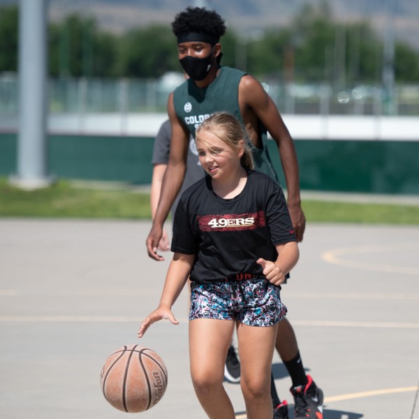 A camper with a counselor playing basketball