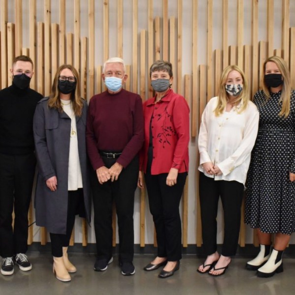 Alumni standing together indoors with masks on