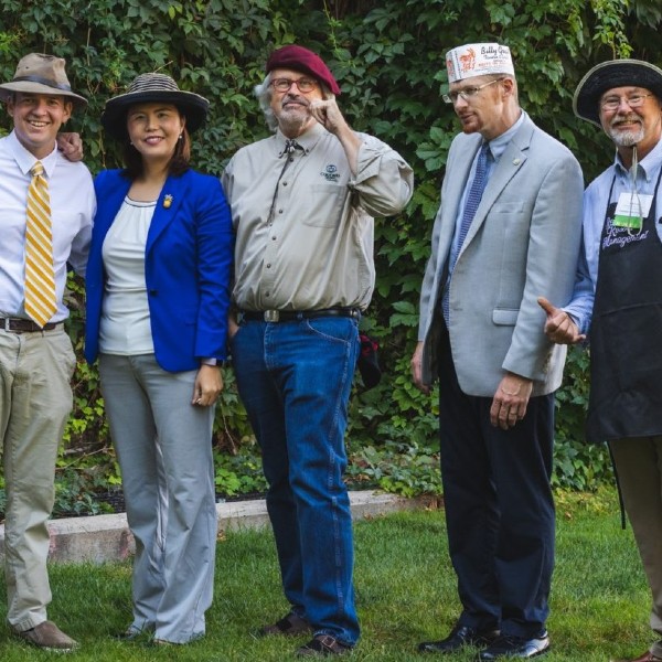 members of the hospitality management faculty posing outside with different hats on