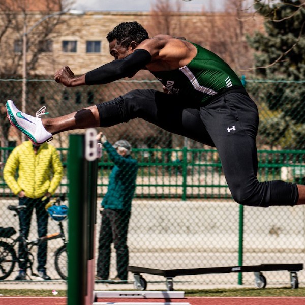 Kamal Craig jumping over a hurdle during a track meet