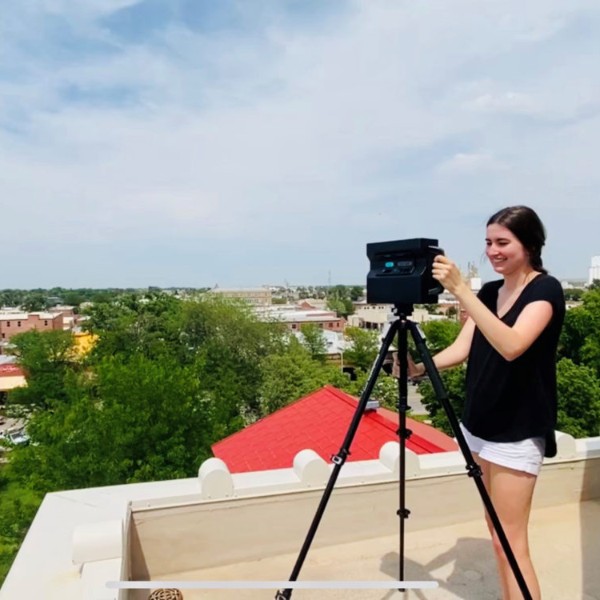 Sara Bovaird working with a camera on a tripod on a roof