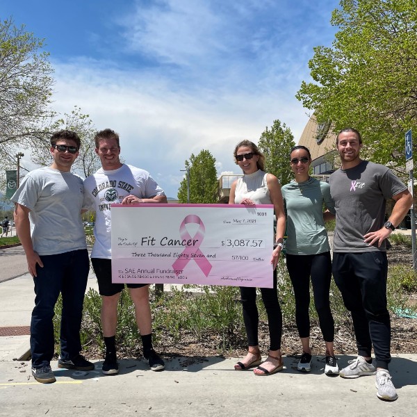Members of a fraternity holding up a large pink check