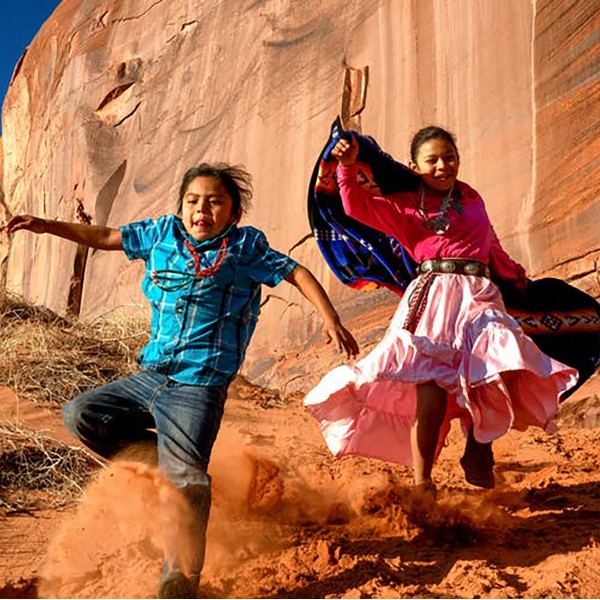 Native American children playing outside in traditional native garb