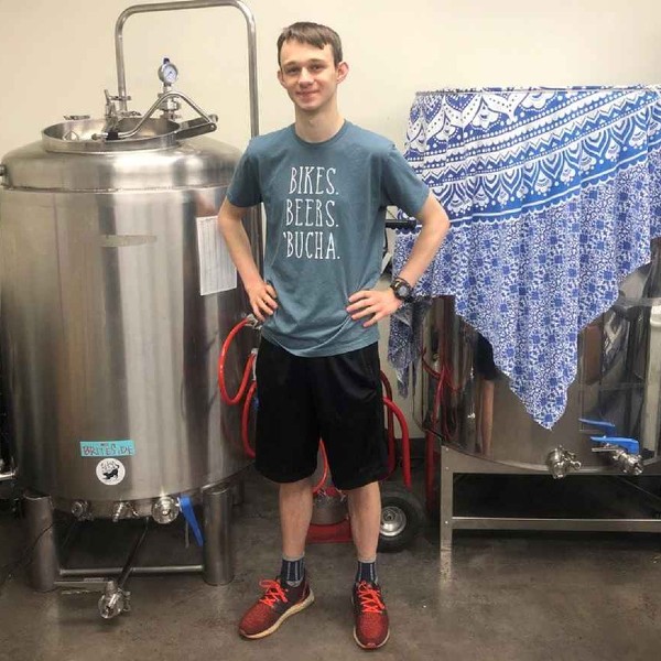A FSHN student interning at a brewery stands in front of a beer tank