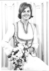 Kristina Aaronson seated wearing her ivory wedding dress holding flowers