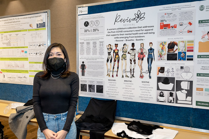 Krista Melusky posing in front of her poster on athletic clothing designs for women