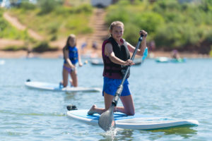 A girl on kneeling on a paddleboard on the water