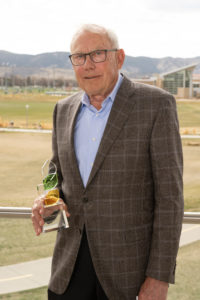 Gordon Marks stands with his CHHS Outstanding Alumnus Award with the CSU campus in the background