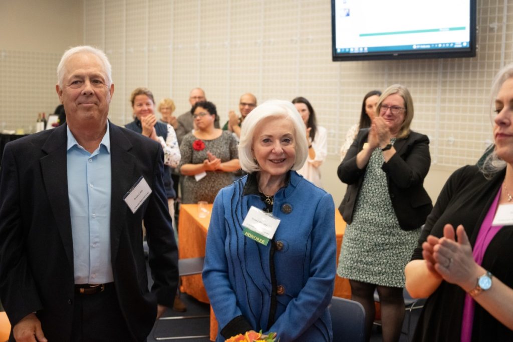 People stand and applaud Nancy Hartley at an event