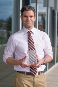 Chris Gentile outdoors holding an award