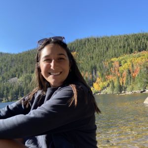 Nikki Casey smiling in front of a lake and fall foliage.