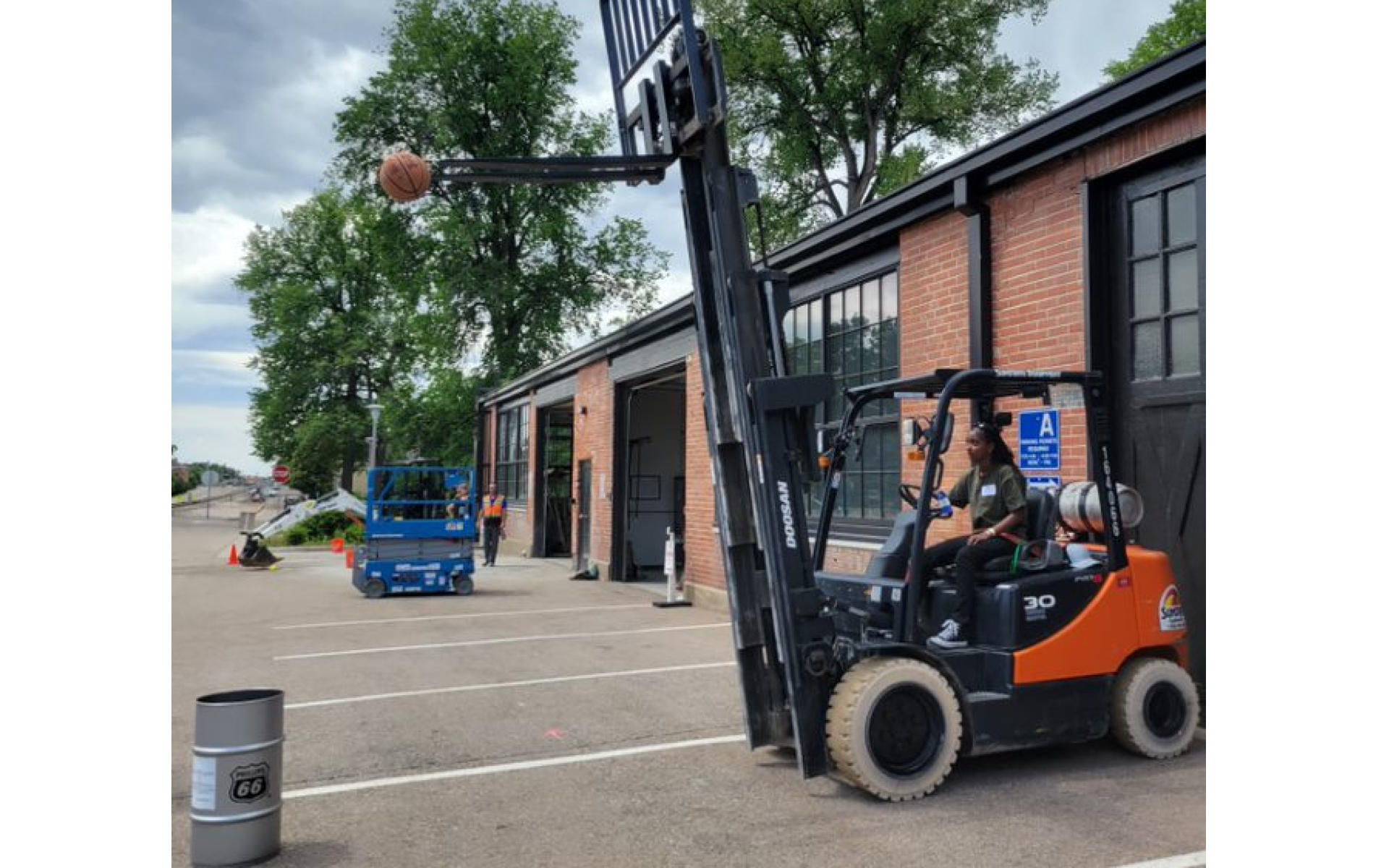 Girl on fork lift with basketball on lifts