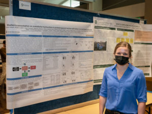 Emily Woolf standing on front of her research poster.