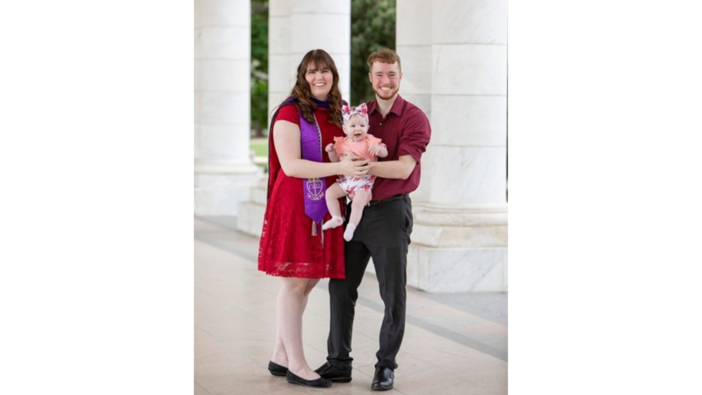 Brittany Anderson standing with her graduation stole holding her baby with her husband.