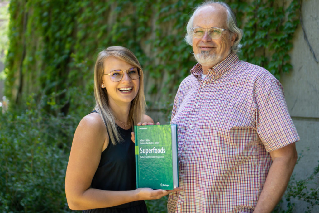 Jeffrey Miller and Charlene Van Buiten stand outside of the Gifford Building holding their new book titled: Superfoods Scientific and Cultural Perspectives