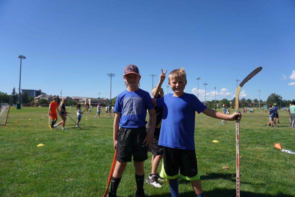 Two campers smile and pose for the camera during their time playing field hockey