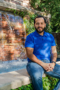 Arnold Cantu poses in front of the Education building waterfall