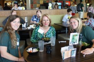 Three women wearing green at a student dining hall