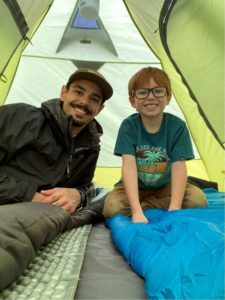 Brendan sitting with his son Alec in a tent 