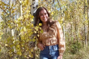 Carissa Weiberg in front of some aspen trees with yellow leaves
