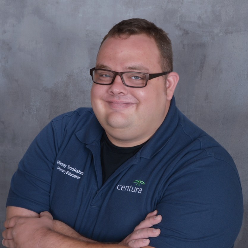 portrait of Wesley Brookshear wearing his Centura work polo shirt and crossing his arms