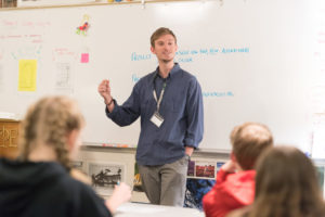 a student teacher presenting to a class of elementary school kids.