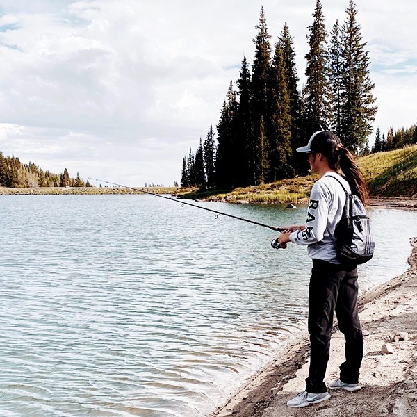Amanda Beaver by a small lake, holding a fishing rod.
