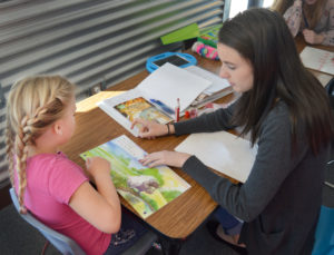 a student teacher and young student read a children's book together