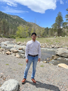 Rayyan Bukhari standing in front of a mountain river