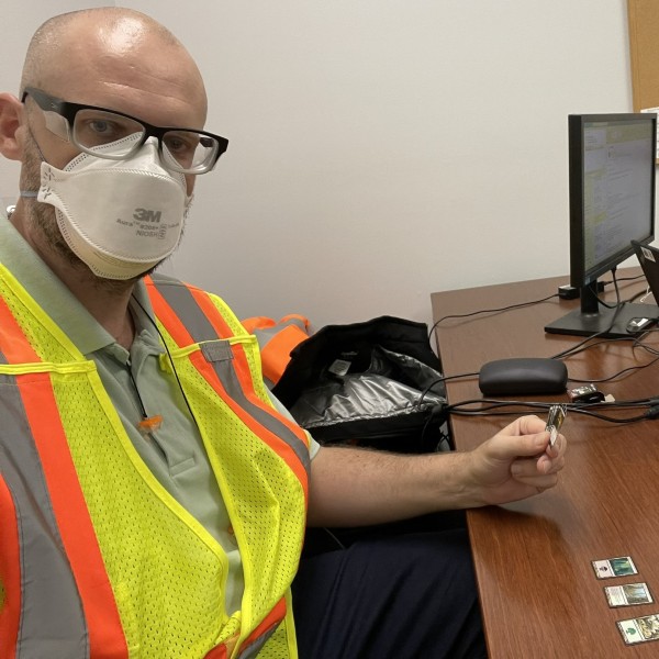 Seth Yoder sitting at a desk with a mask and vest on