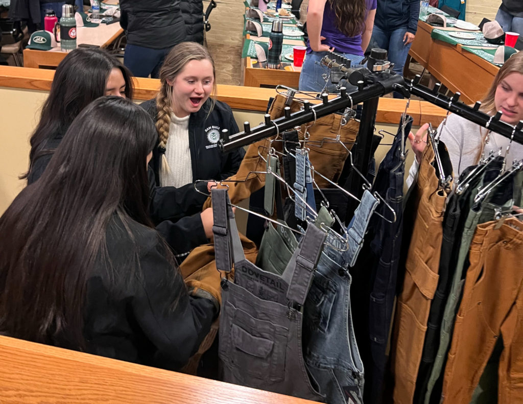 Four female students shopping the clothing on racks