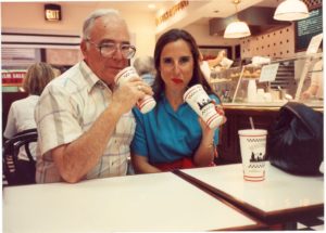 A man and his adult daughter both sip through straws at a soda fountain.