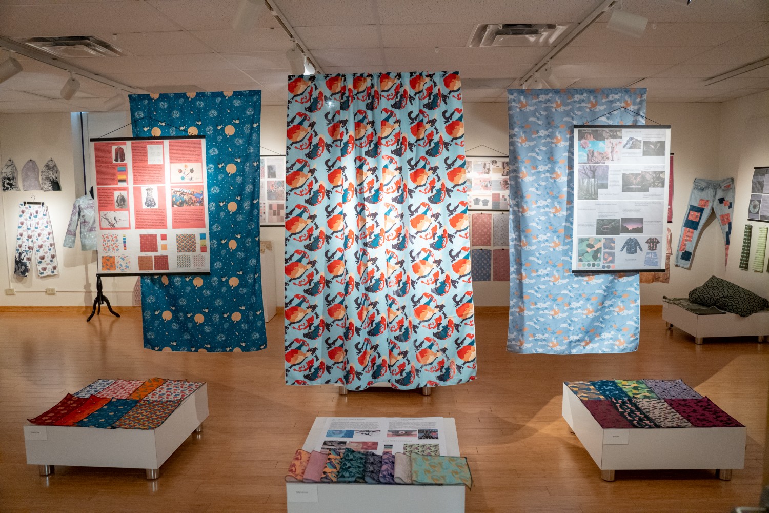 Colorful textiles hanging from the ceiling in a gallery
