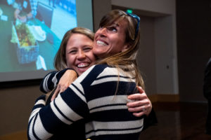 Two women hug and smile at an event