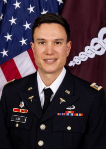 Portrait of a man in a US Army uniform with flags behind him.