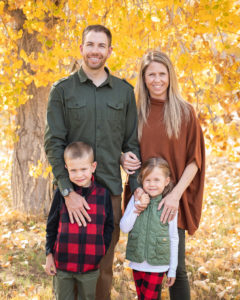 A young family poses for a portrait with yellow autumn leaves