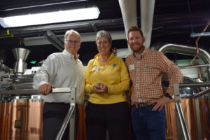 Jeff McCubbin, Jeannie Miller, and Jeff Callaway standing in front of brewing tanks