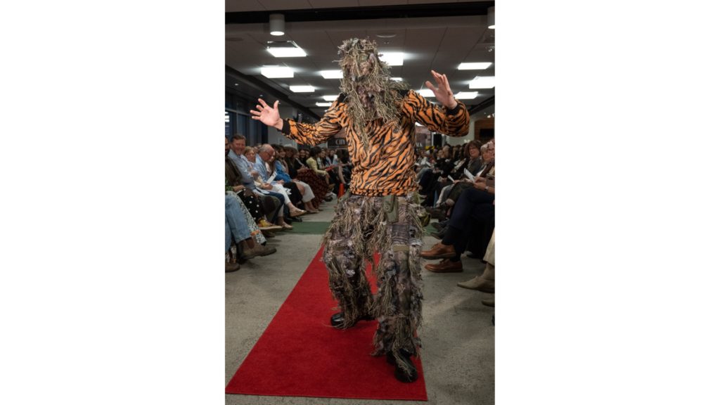 A student at the CSU fashion show is pictured modeling a Ghillie Suit with a tiger print long sleeve shirt.