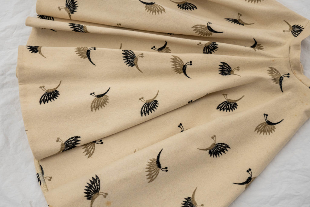 An ivory, wool skirt with a pattern of embroidered moths.